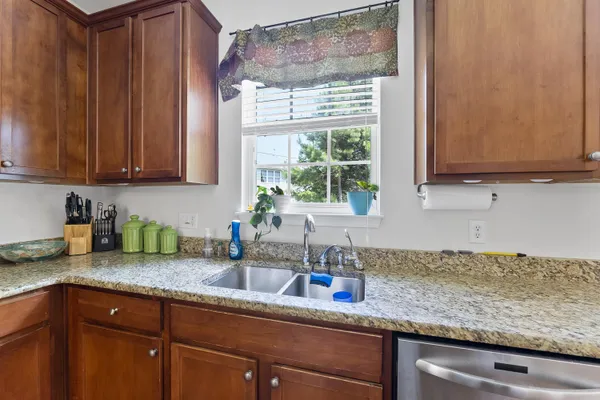 a kitchen with granite countertop stainless steel appliances a sink window and cabinets