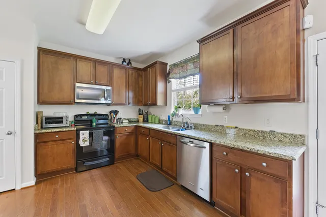 a kitchen with granite countertop wooden cabinets a sink a stove a refrigerator and island