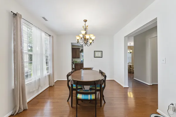 a dining room with wooden floor a chandelier a wooden table and chairs