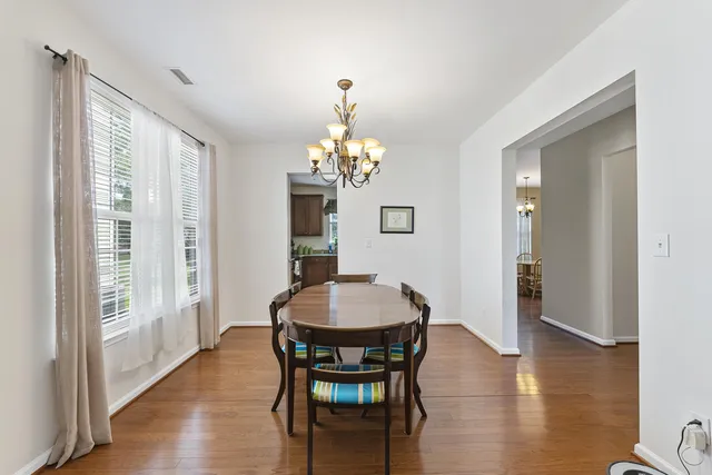 a dining room with wooden floor a chandelier a wooden table and chairs