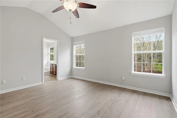 an empty room with wooden floor chandelier fan and windows