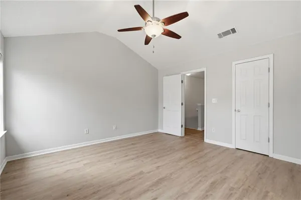 an empty room with wooden floor and ceiling fan