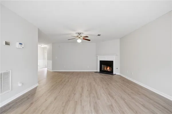 a view of an empty room with wooden floor fireplace and a window