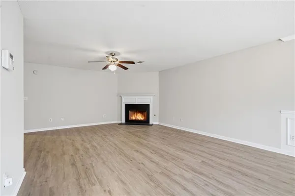 a view of an empty room with wooden floor and fireplace