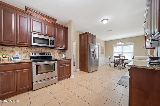 a kitchen with granite countertop a refrigerator and a stove top oven