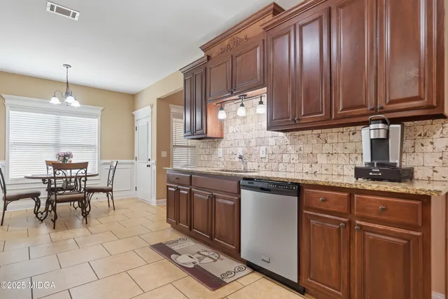a kitchen with stainless steel appliances granite countertop wooden cabinets a dining table and chairs
