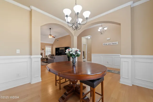 a dining room with wooden floor a chandelier a wooden table and chairs