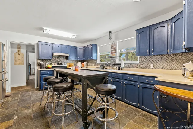 a kitchen with stainless steel appliances granite countertop table chairs sink refrigerator and cabinets