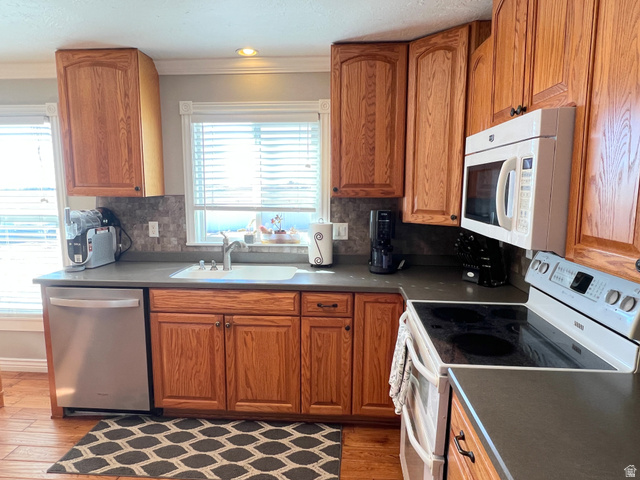 1852 East 3500th Street South Vernal, UT 84078 - Photo 16 of 46 Kitchen with white appliances, dark countertops, wood finish cabinets, wood finished floors, and crown molding