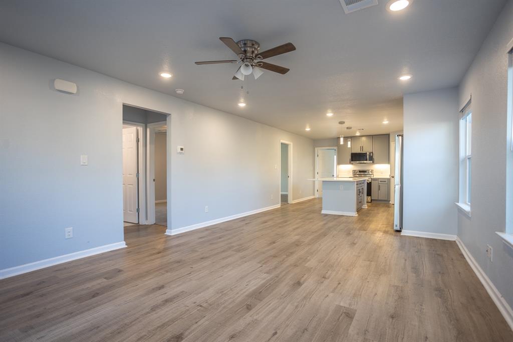 815 Ritchey Street Gainesville, TX 76240 - Photo 6 of 18 a view of an empty room and kitchen with wooden floor