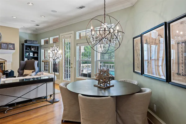 a dining room with wooden floor a chandelier a wooden table and chairs