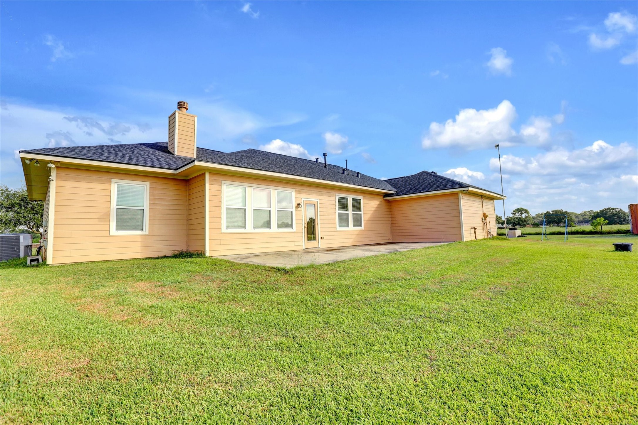 8131 Brinkmeyer Road Needville, TX 77461 - Photo 14 of 49 Spacious backyard with a patio, perfect for outdoor activities, complements this charming home's exterior.