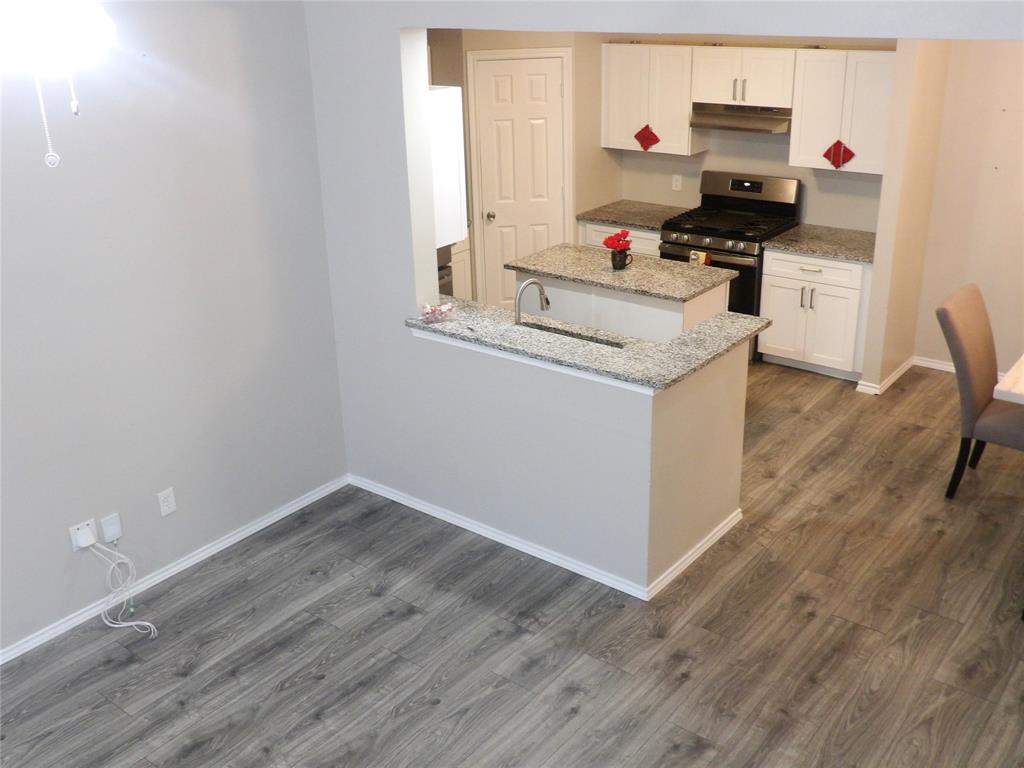 223 Juniper Ridge Court DeSoto, TX 75115 - Photo 32 of 33 Kitchen featuring light stone counters, stainless steel gas range oven, white cabinets, dark wood-style flooring, and a peninsula