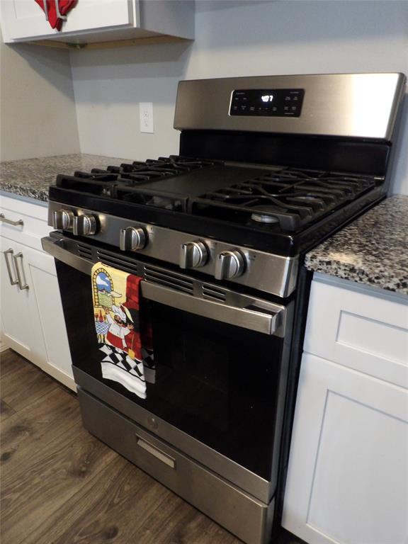 223 Juniper Ridge Court DeSoto, TX 75115 - Photo 10 of 33 Kitchen with stainless steel gas range oven, white cabinetry, dark stone counters, and dark wood-style floors