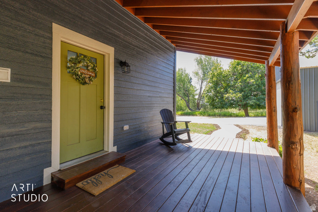 2807 North Ogden Canyon Road Eden, UT 84310 - Photo 49 of 72 Covered porch featuring a vibrant green door with an overhead transom window, dark wood-finish decking, and exposed timber columns