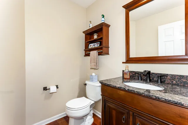 a bathroom with a granite countertop sink and a toilet