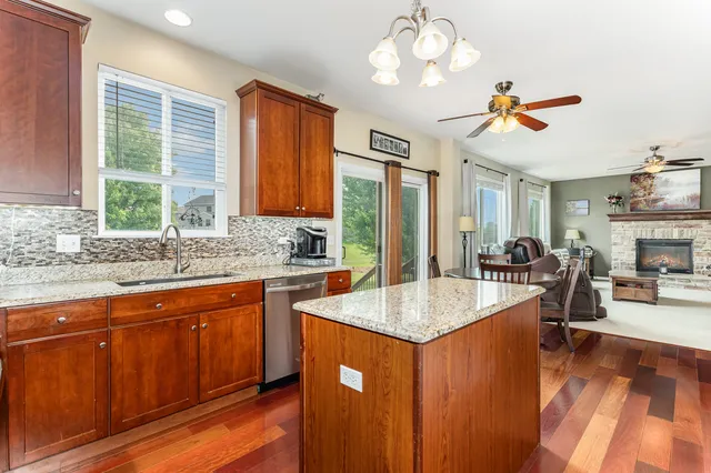 a very nice looking kitchen with granite countertop a stove two sinks a dining table and chairs