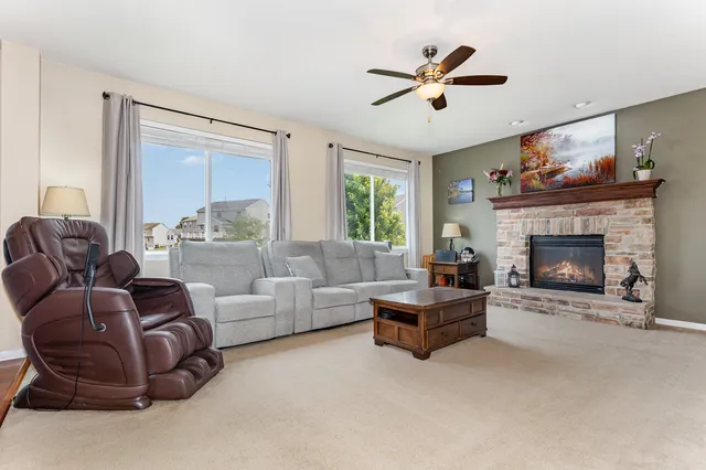 a living room with furniture a ceiling fan and a fireplace