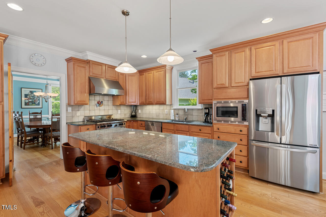 30119 Settle Chapel Hill, NC 27517 - Photo 17 of 49 a kitchen with stainless steel appliances granite countertop a sink a stove a refrigerator a center island with wooden floor and cabinets