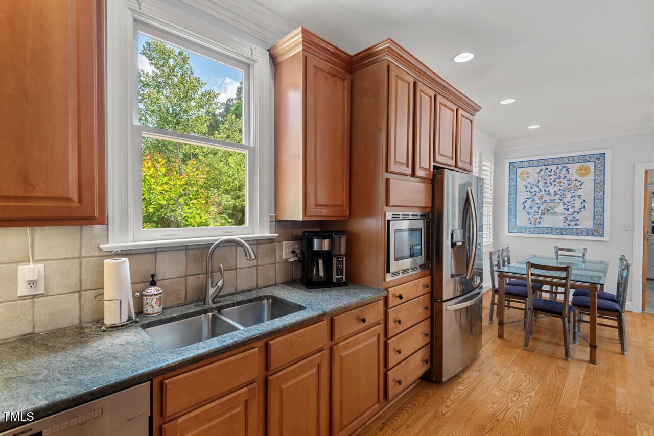 30119 Settle Chapel Hill, NC 27517 - Photo 19 of 49 a kitchen with stainless steel appliances granite countertop a refrigerator a sink dishwasher a stove a dining table and chairs with wooden floor