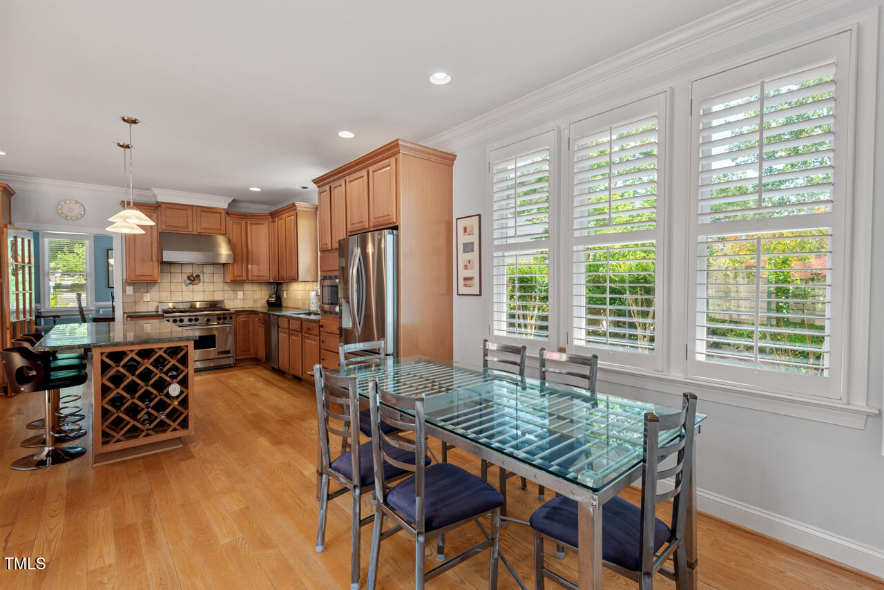 30119 Settle Chapel Hill, NC 27517 - Photo 23 of 49 a kitchen with stainless steel appliances granite countertop a stove a refrigerator a dining table and chairs with wooden floor