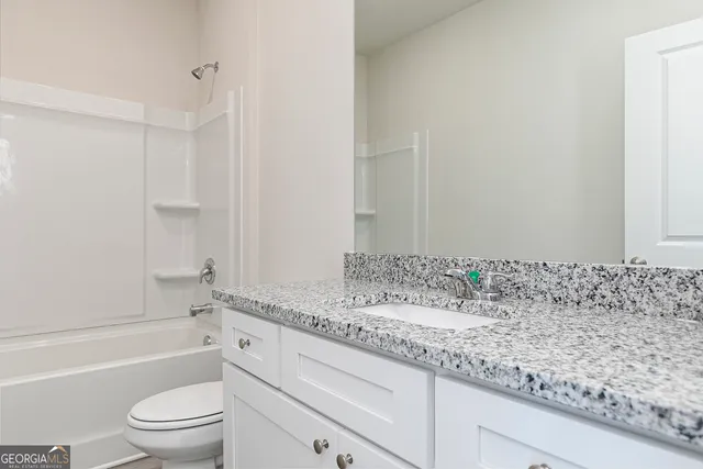 a bathroom with a granite countertop sink a toilet and bathtub