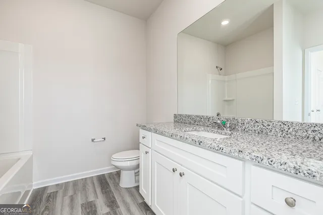 a bathroom with a granite countertop sink a toilet and a shower