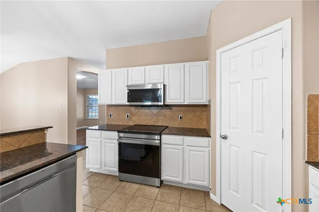 a kitchen with white cabinets and stainless steel appliances