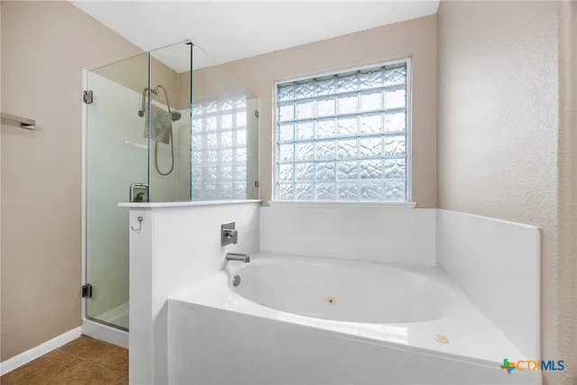 a bathroom with a bathtub a shower and a window