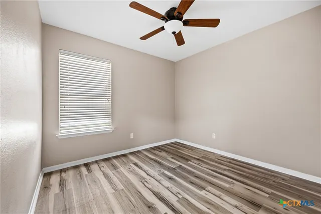 an empty room with a window and a fan