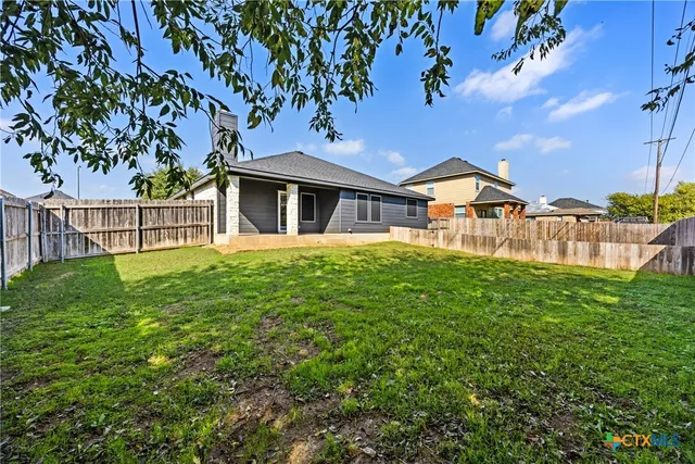 a view of a house with a small yard and a large tree