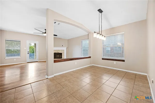 a view of an empty room with kitchen and window