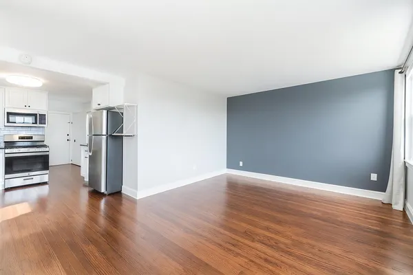 an empty room with wooden floor fan and windows