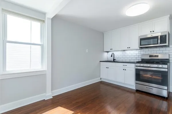 a kitchen with stainless steel appliances a stove a microwave and white cabinets