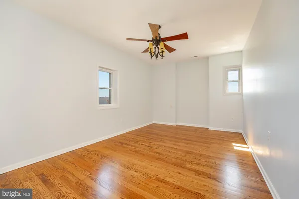 a view of a big room with wooden floor and windows