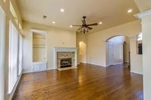 a view of a livingroom with a fireplace a ceiling fan and wooden floor