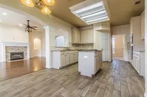 a kitchen with granite countertop a refrigerator a sink dishwasher a stove and white cabinets with wooden floor
