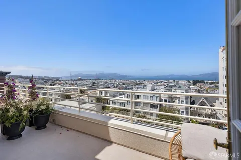 a view of a city from a balcony with outdoor seating