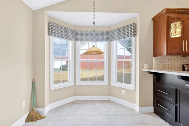 a view of an empty room with a window and kitchen view