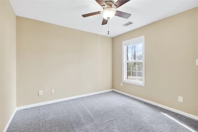 an empty room with a chandelier fan and windows