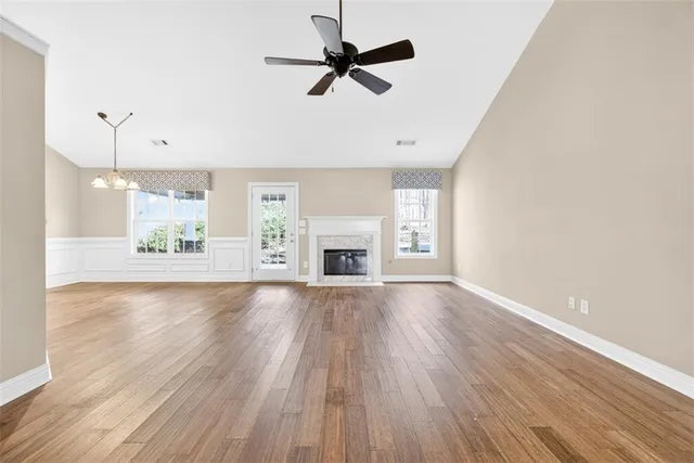 an empty room with wooden floor fan and windows