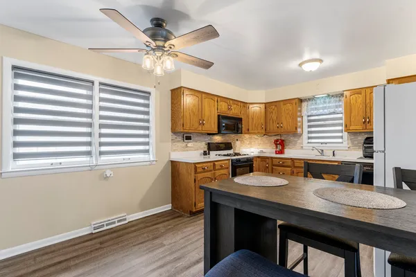 a kitchen with granite countertop a stove a sink dishwasher a refrigerator with wooden cabinets and wooden floor