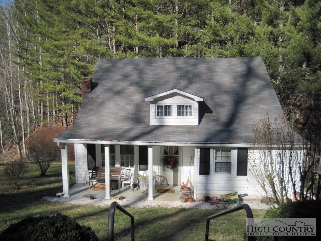 a front view of a house with yard and trees in the background
