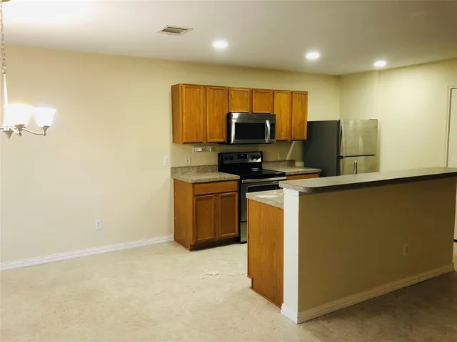 a kitchen with stainless steel appliances a stove top oven a sink a refrigerator and a microwave