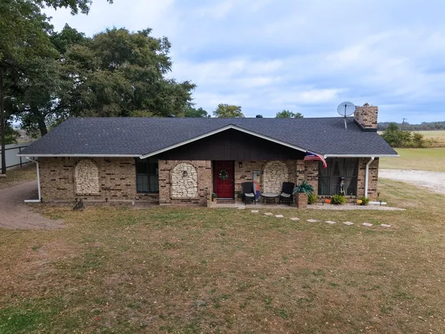 a front view of house with yard and trees in the background
