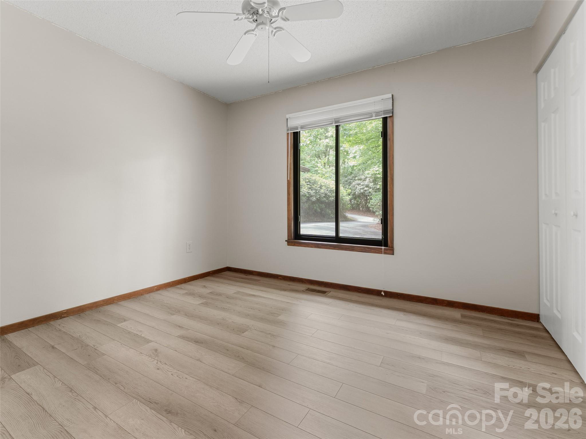 32 Honey Suckle Ridge Road Pisgah Forest, NC 28768 - Photo 22 of 35 an empty room with wooden floor chandelier fan and windows