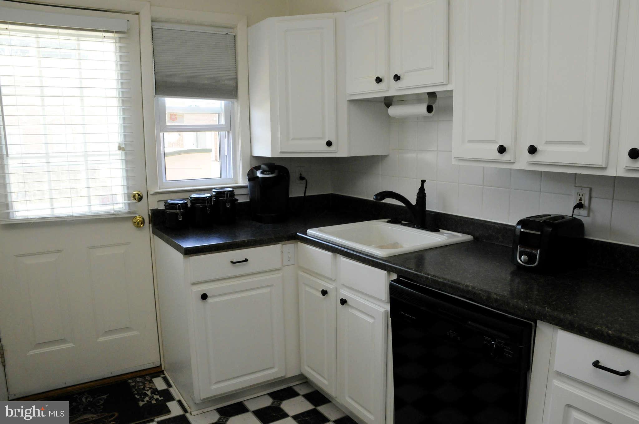 516 Queensgate Road Baltimore, MD 21229 - Photo 14 of 27 a kitchen with a sink dishwasher a stove and white cabinets