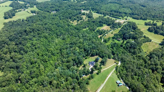 an aerial view of residential house with outdoor space and trees all around