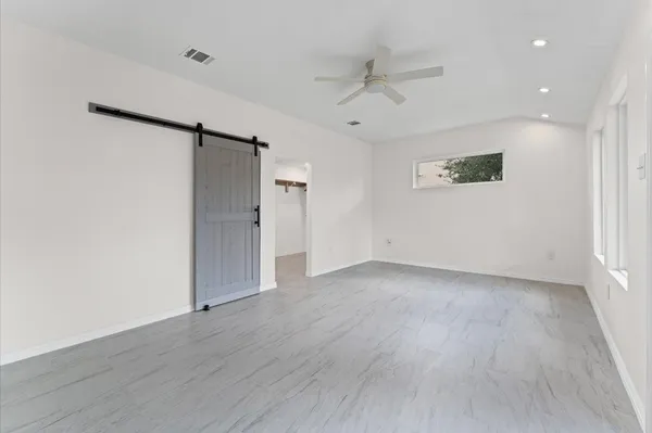 an empty room with wooden floor and ceiling fan