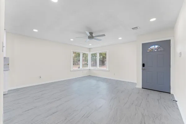 an empty room with wooden floor a ceiling fan and windows